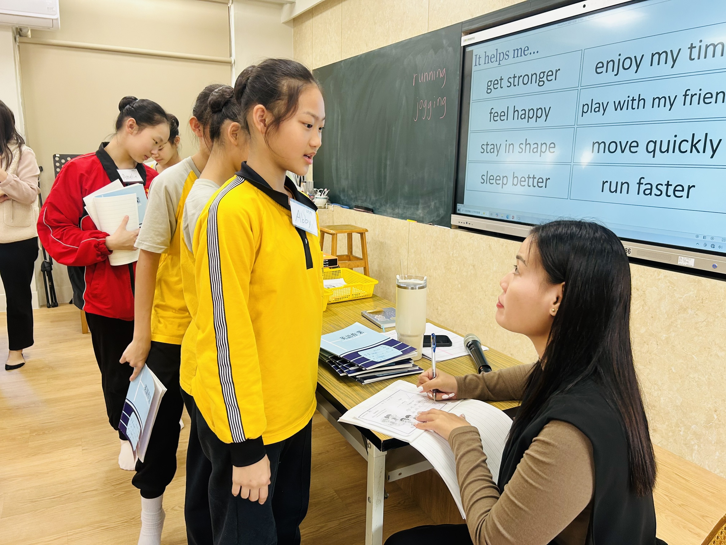 The teacher checks students’ workbooks